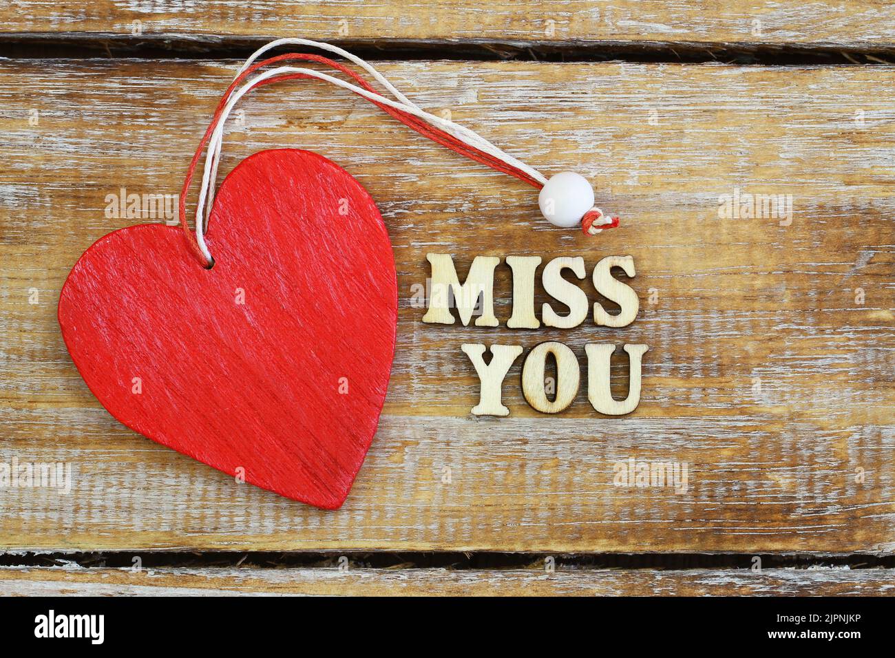 Miss you written with wooden letters and red wooden heart on rustic surface Stock Photo