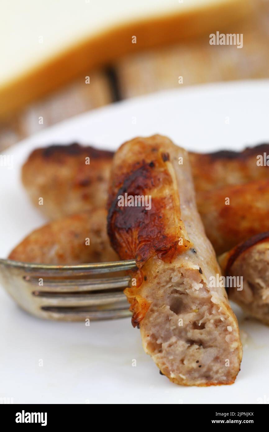Close up of crispy, fried British pork sausage on fork Stock Photo