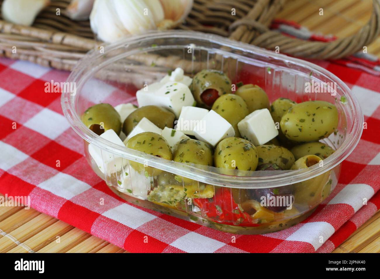 Green olives and pieces of feta cheese in transparent plastic box Stock Photo