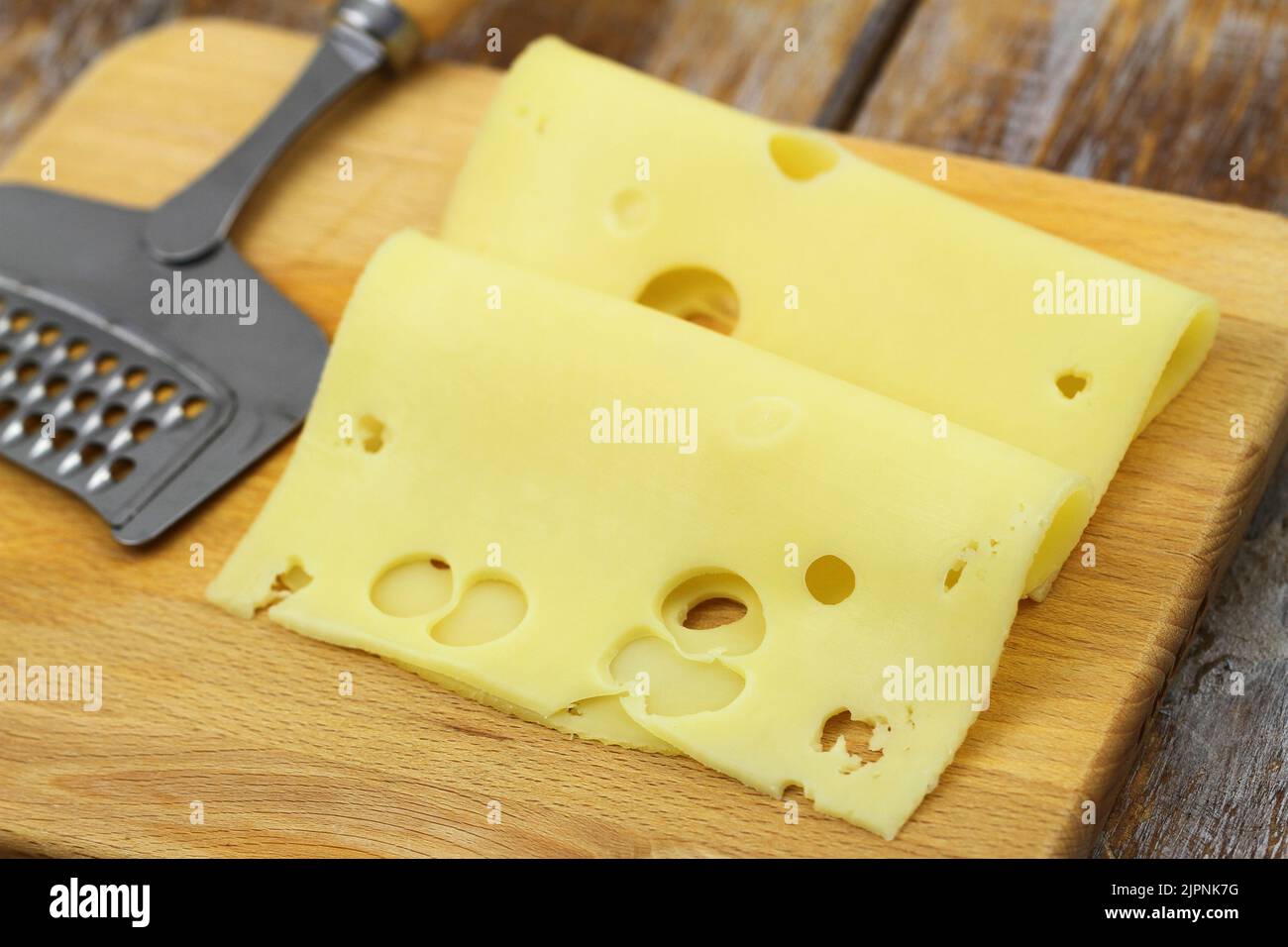 Slices of tasty Swiss cheese on wooden board Stock Photo