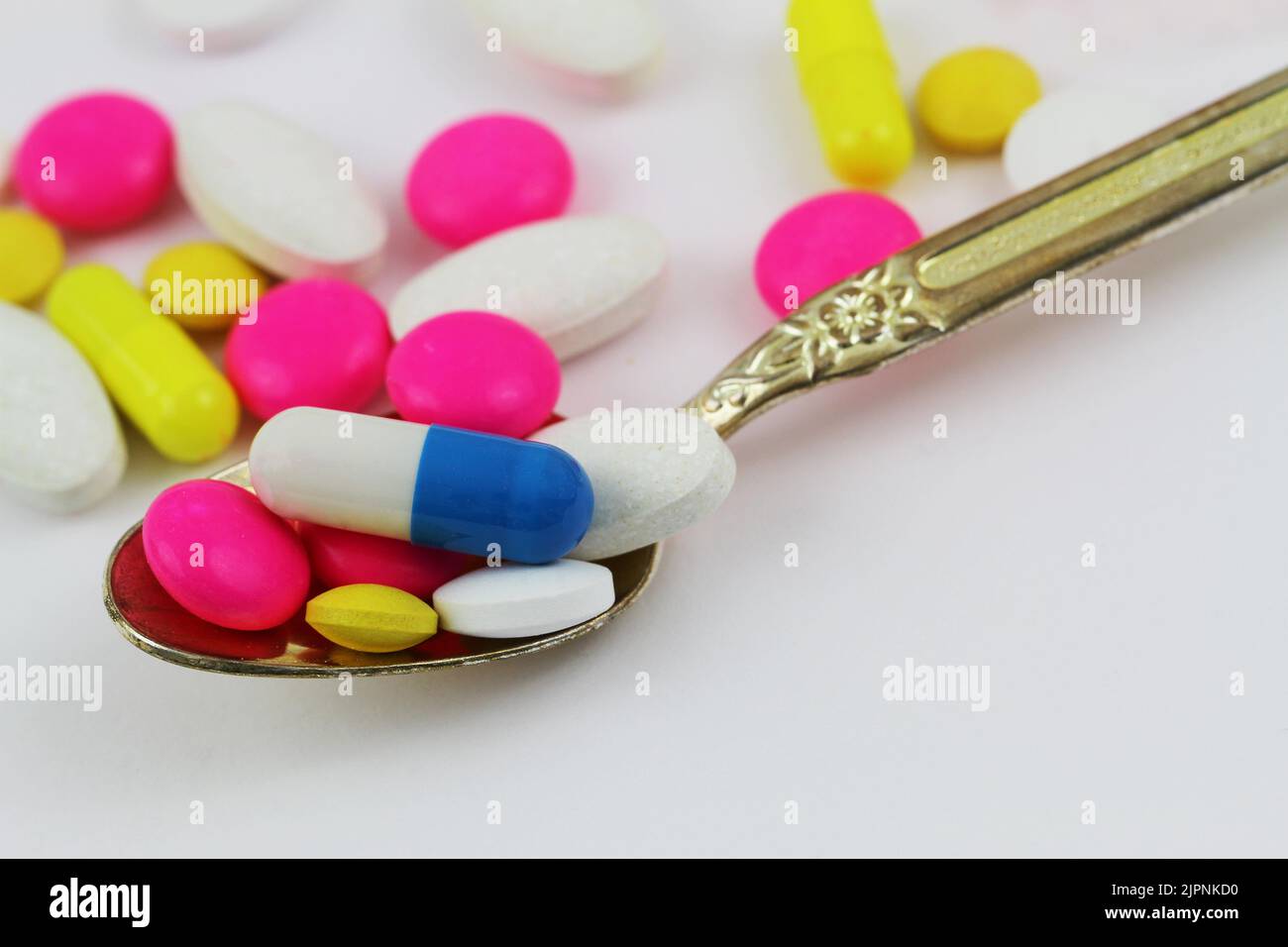 Spoon full of different colorful pills, closeup Stock Photo