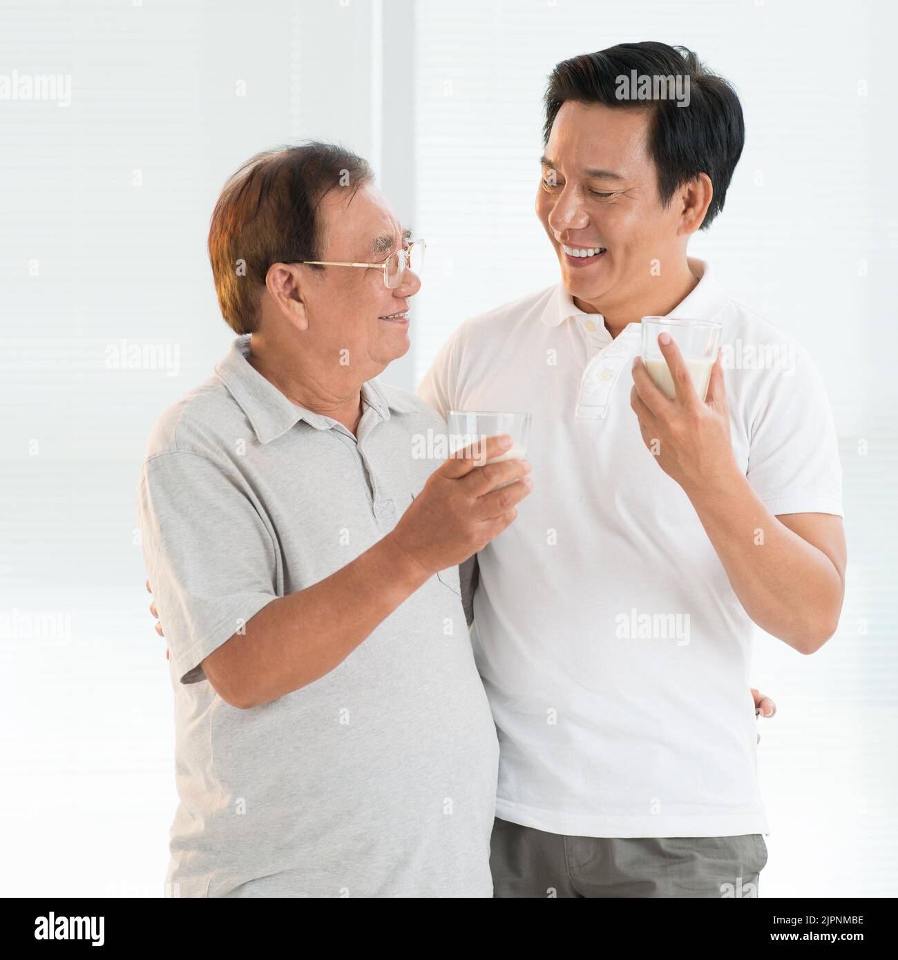 Happy senior man and his adult son drinking milk Stock Photo