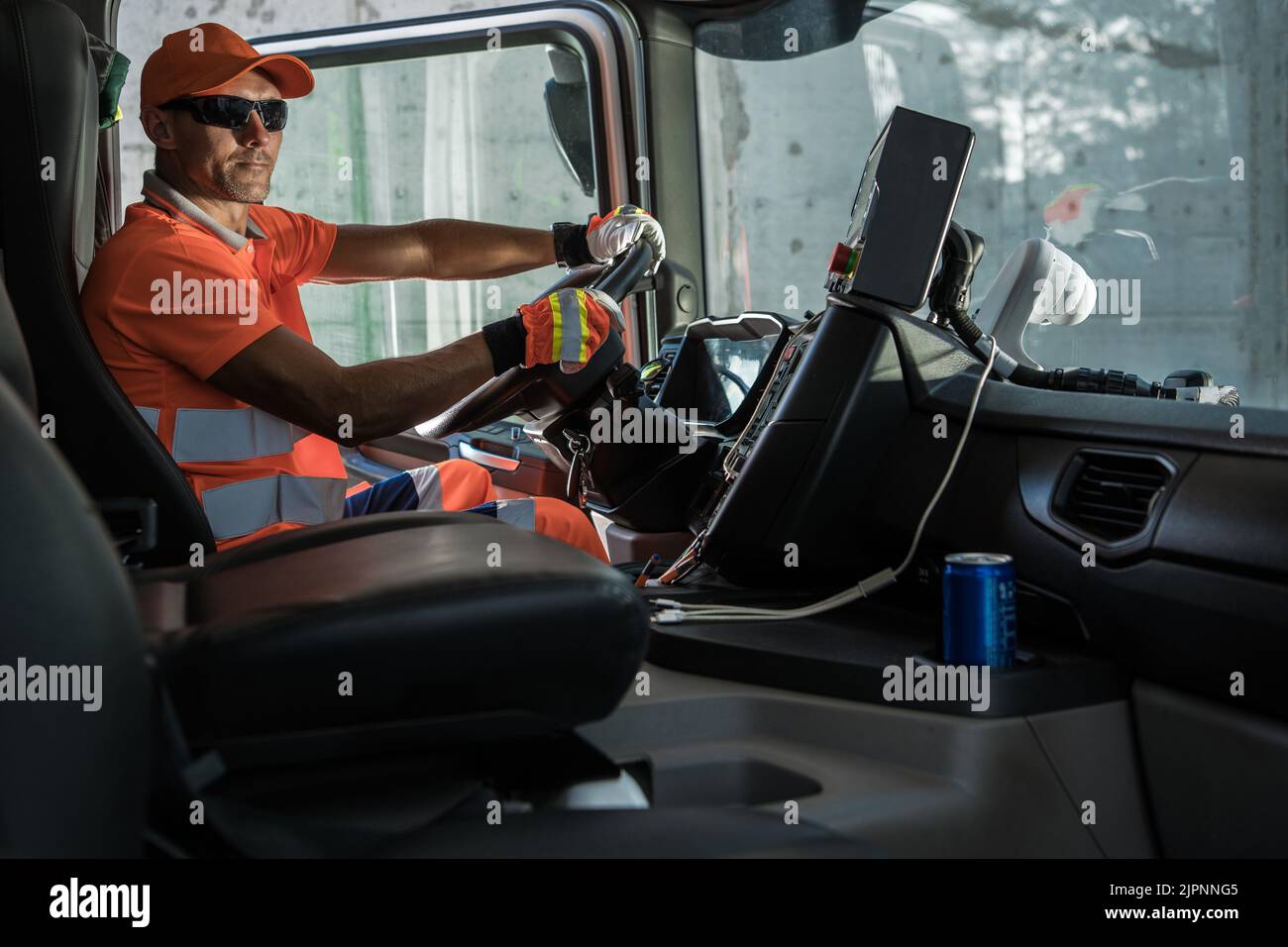 Modern Caucasian Garbage Truck Driver Behind the Wheel. Waste Transport and Management Industry Job. Trash Sorting Facility Delivery. Stock Photo