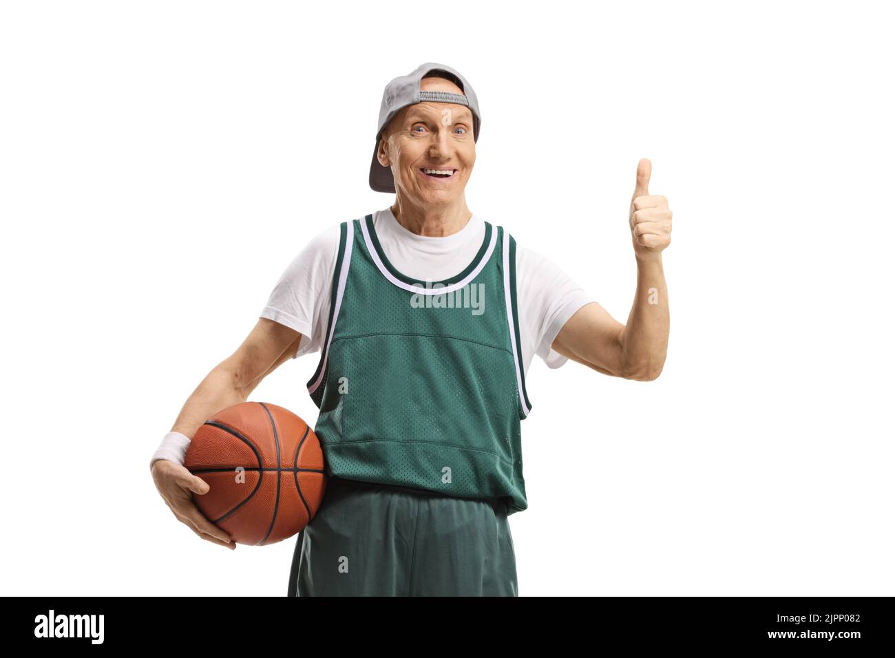 Elderly man in a green jersey holding a basketball and showing thumbs up isolated on white background Stock Photo