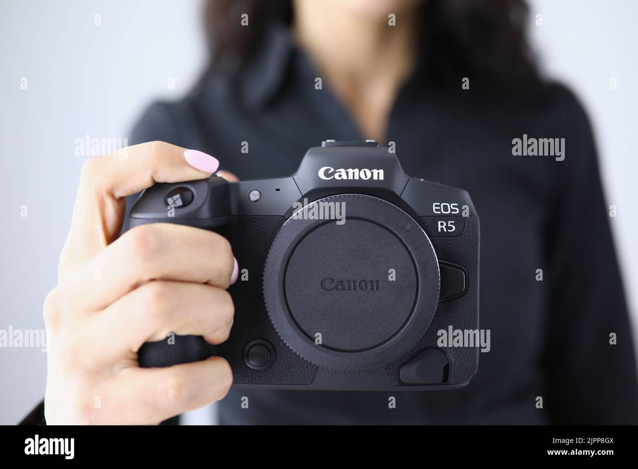 Tbilisi, Georgia - July 26, 2022: Person holding modern Canon EOS R5 camera closeup in hand Stock Photo