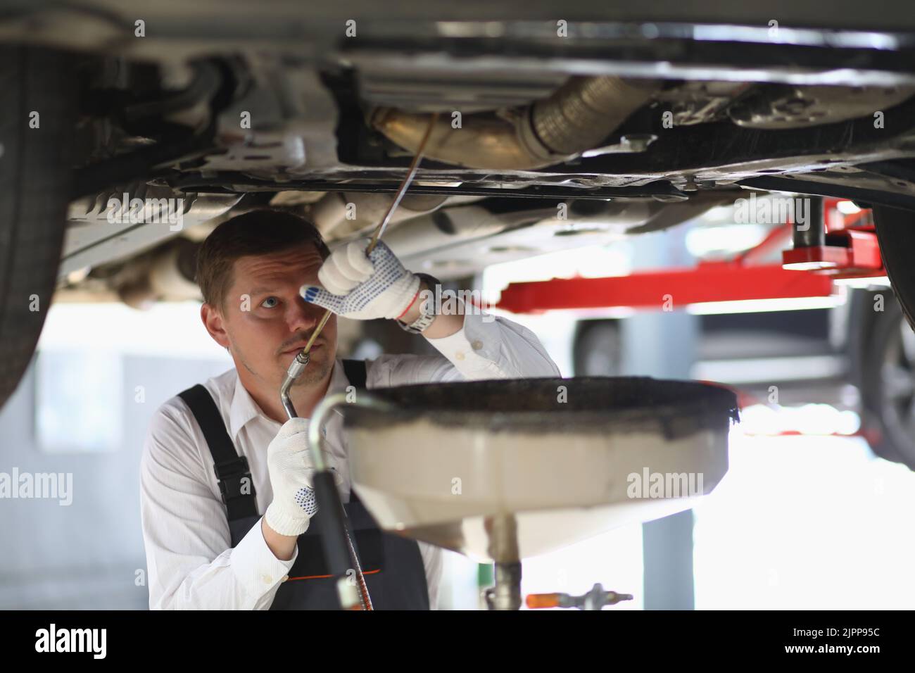 Auto mechanic checks running gear of car and oil leak at service