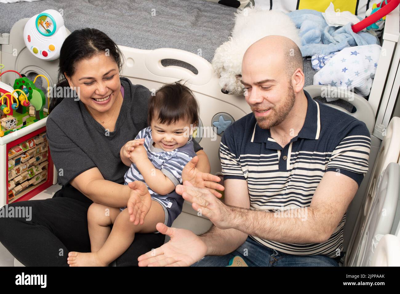 11 month old baby boy at home with parents singing song with hand gestures Stock Photo