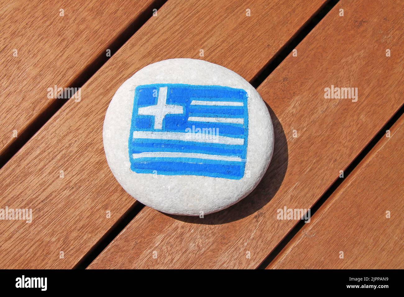 Greece country flag painted on the sea stone on wooden plank background. Stock Photo