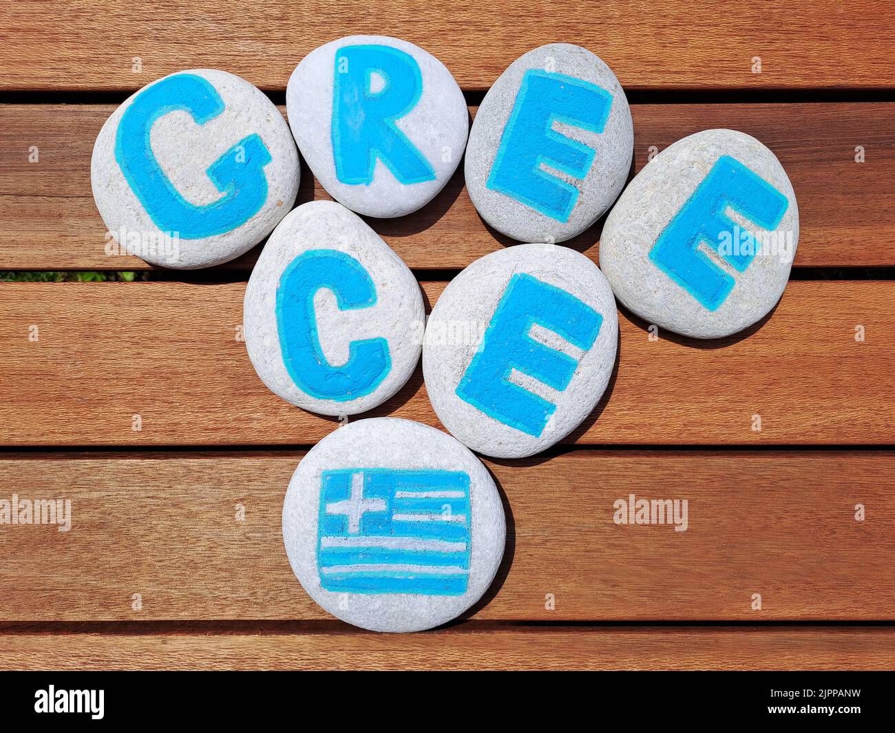 Greece country name painted on the stones on wooden plank background. Inskription on the sea stones. Stock Photo