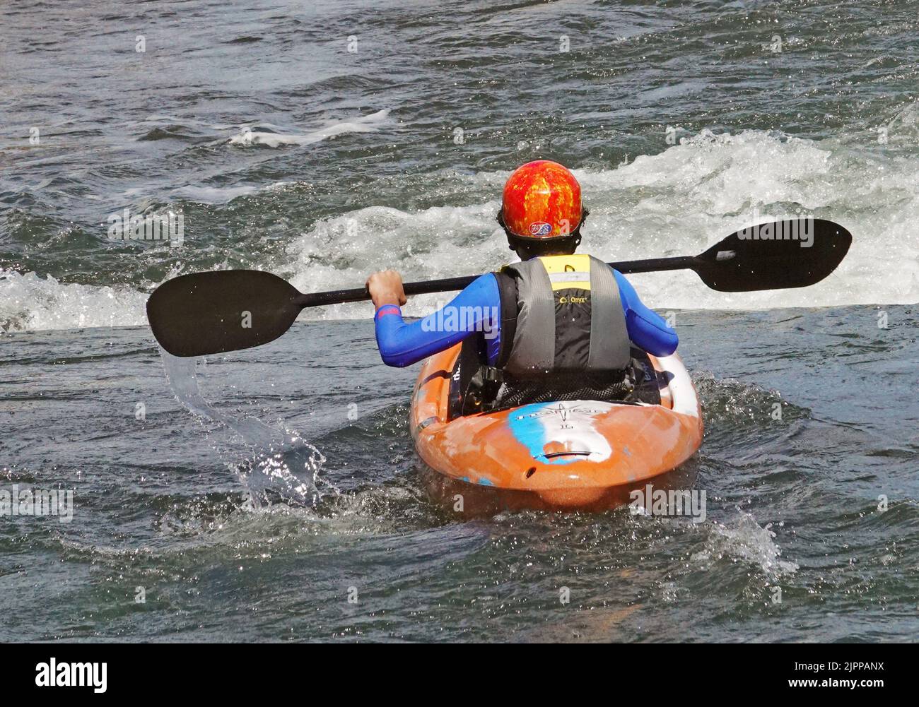 A kayaker runs a small set of rapids at a waterprk on the Deschutes River in Bend, Oregon. Stock Photo