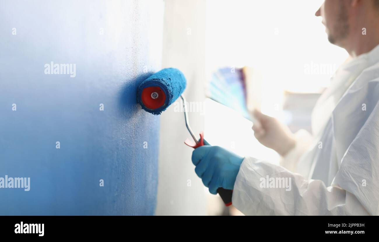 Painting white wall with blue roller closeup Stock Photo