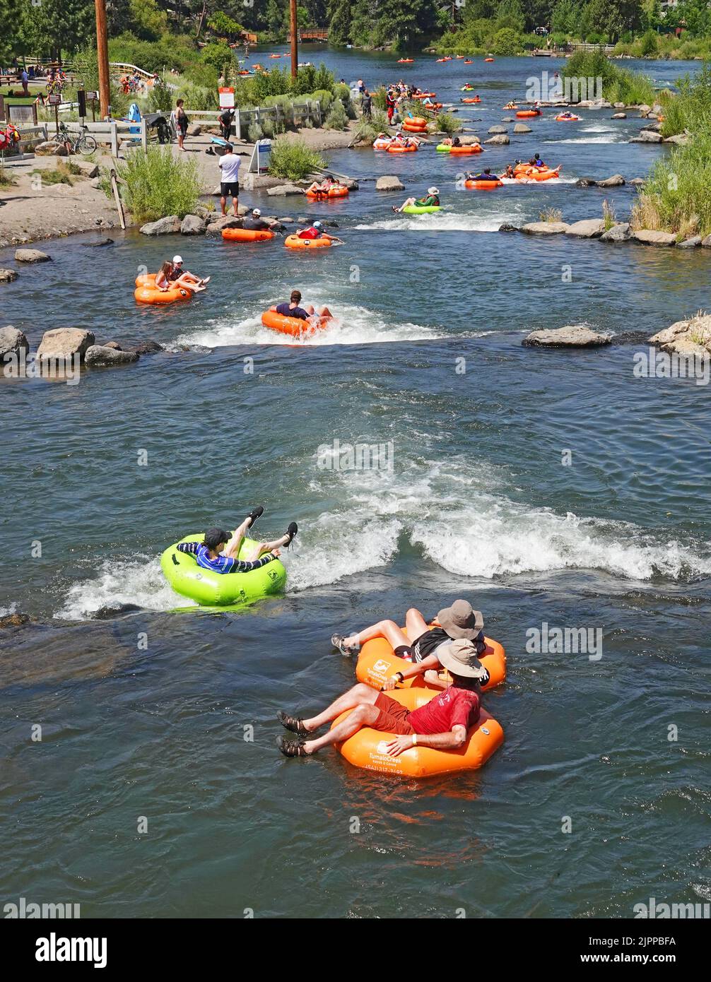 Beating the heat in the American Pacific Northwest. The state of Oregon and the Pacific Northwest in general is undergoing another major heatwave with temperatures reaching 100 degrees farenheit plus during the afternoons. Floating the river is a popular way to cool off. This is the Deschutes River in Bend, Oregon. Stock Photo
