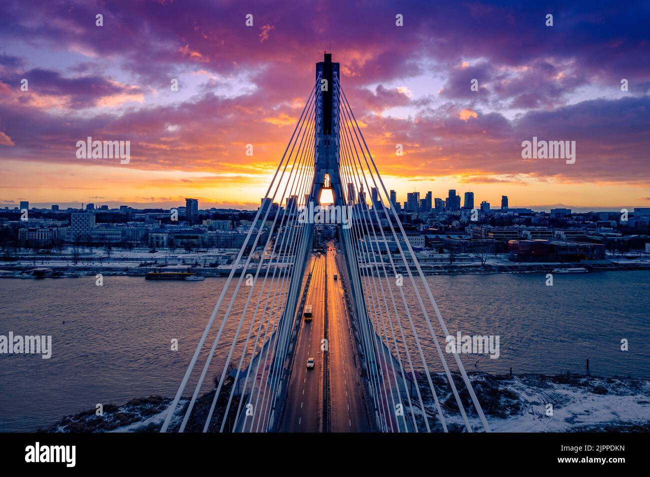 A scenic view of purple sunset over the city and a bridge connecting ...