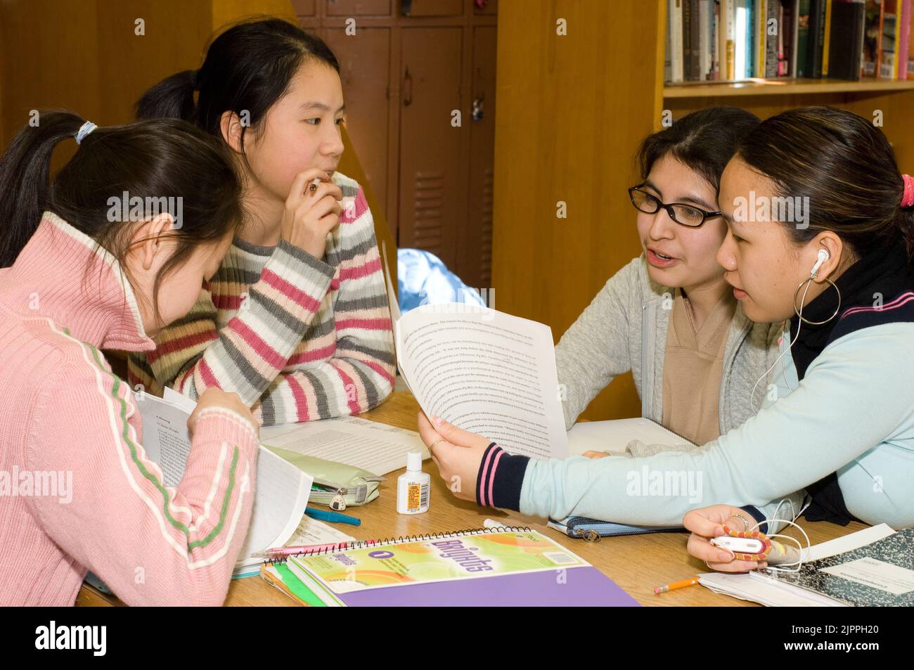 Public School High School group of female students discussing a paper, sitting at table in classroom Stock Photo