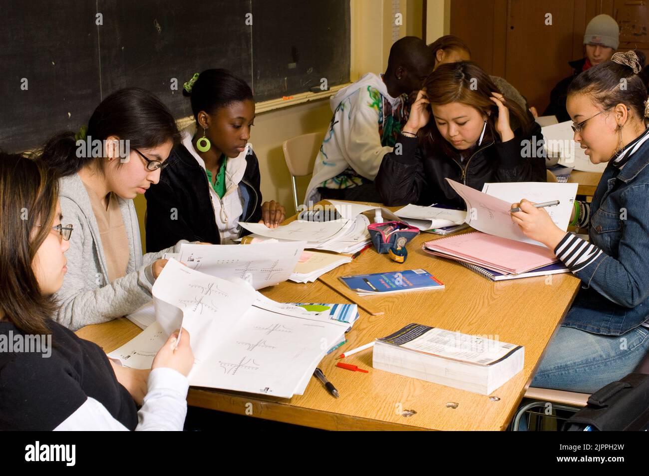 Education HIgh School classroom mathematics or science female students looking at charts or graphs on papers in front of them during class Stock Photo