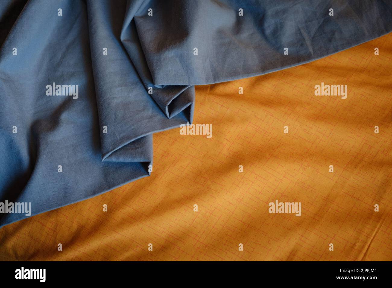 Bicolor background gray orange fabric, crumpled fabric folds, selective focus Stock Photo
