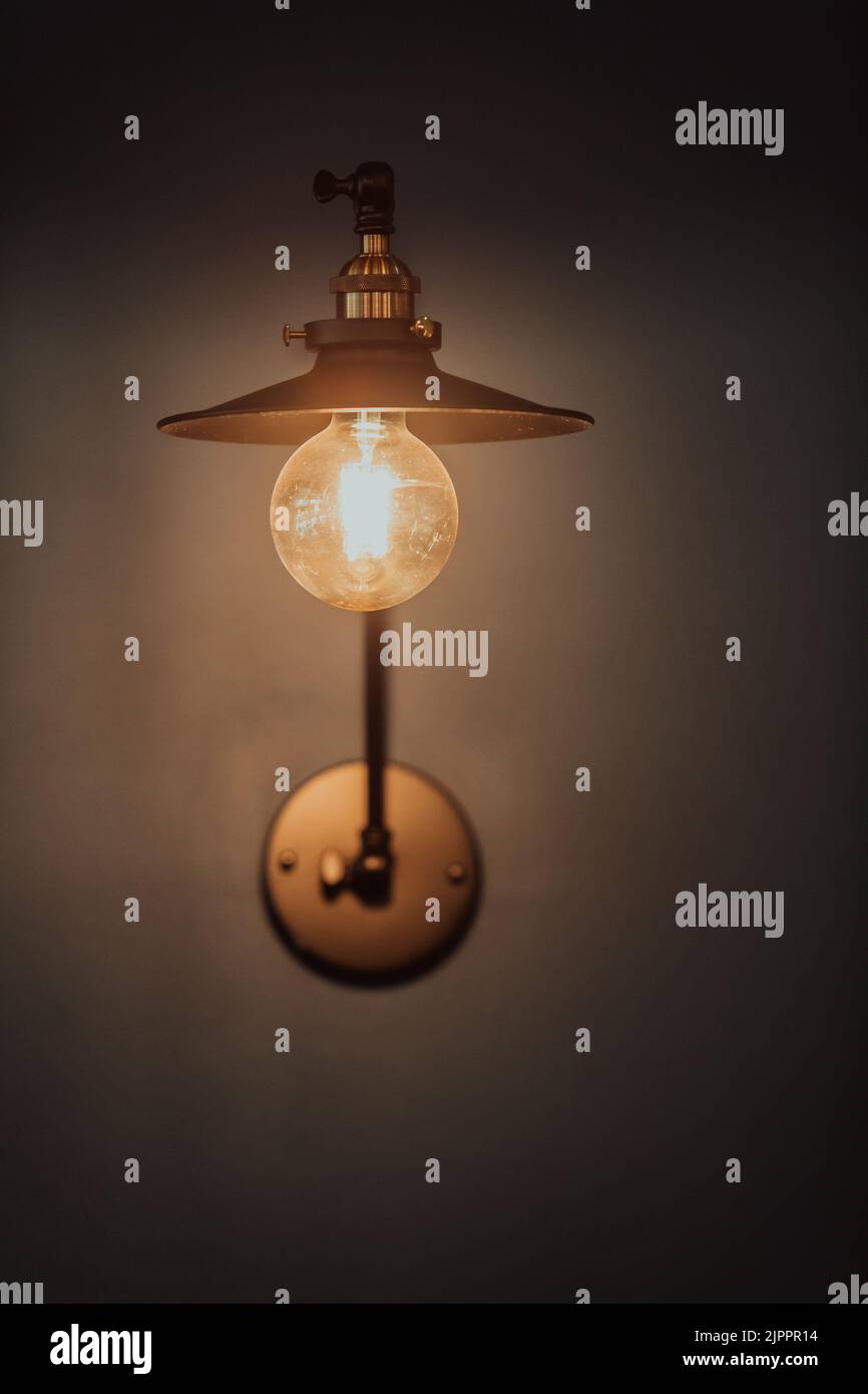 Old light bulb on a modern blue wall. Selective focus  Stock Photo