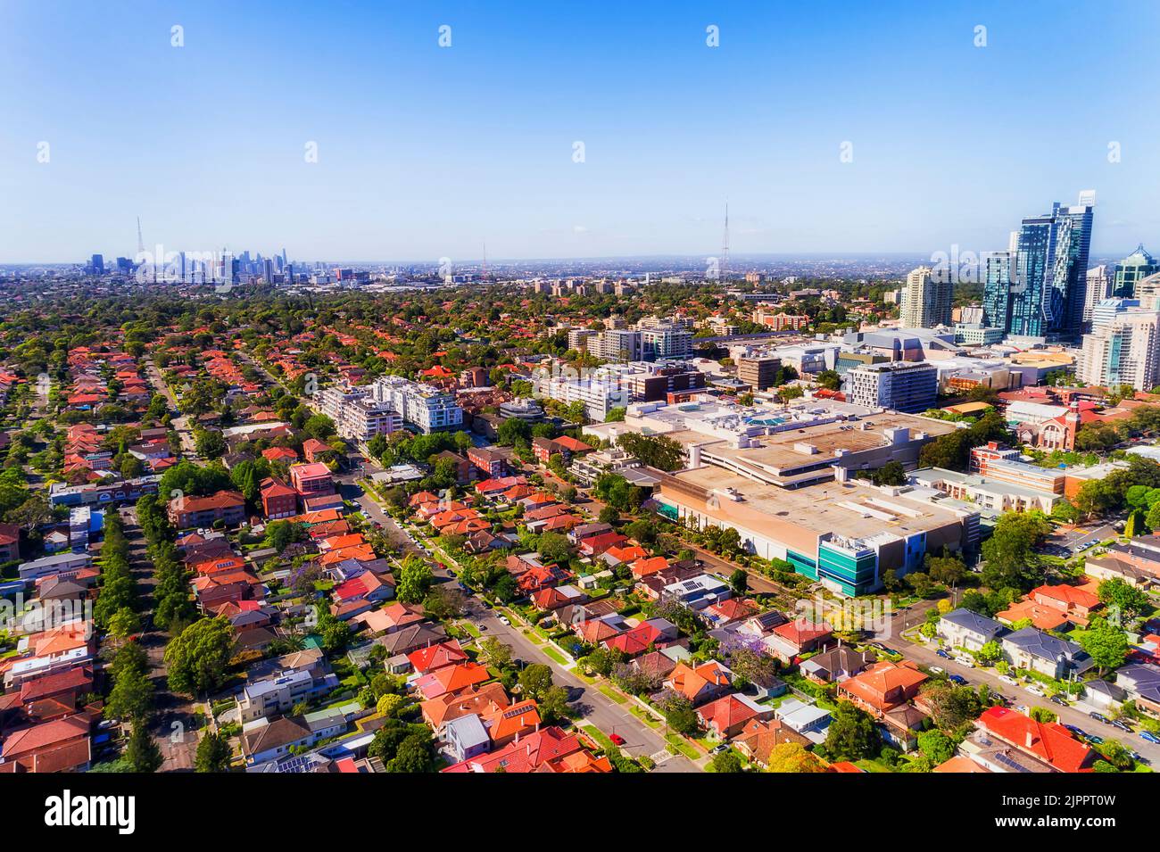 Aerial view of Chatswood modern business district and distant Sydney city CBD in aerial view on a sunny day. Stock Photo