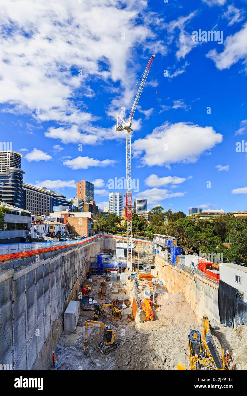 Deep excavated pit on construction site with crane and machinery