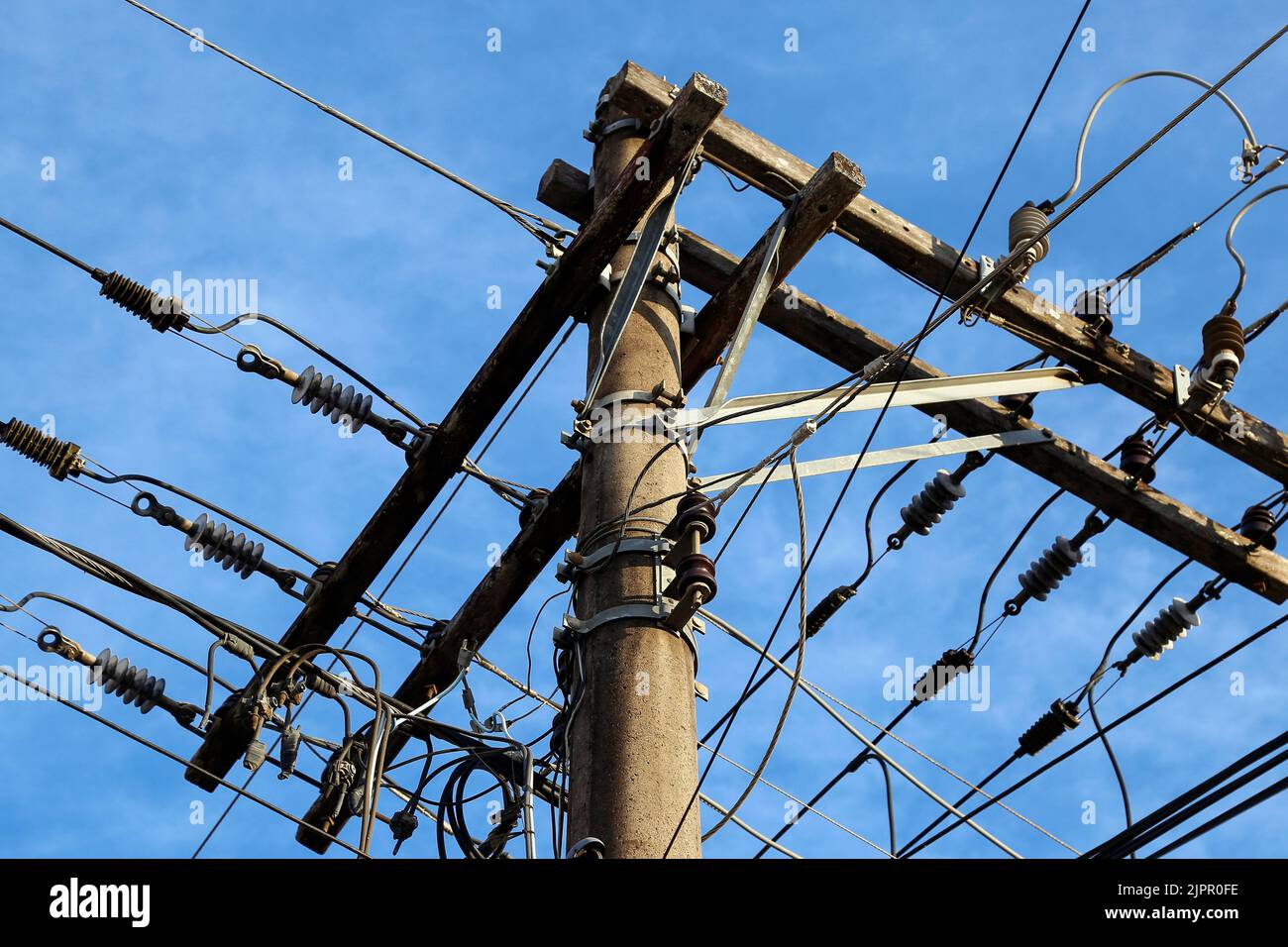 concrete pole with electrical power, telephony and fiber optic cabling - electricity concept Stock Photo