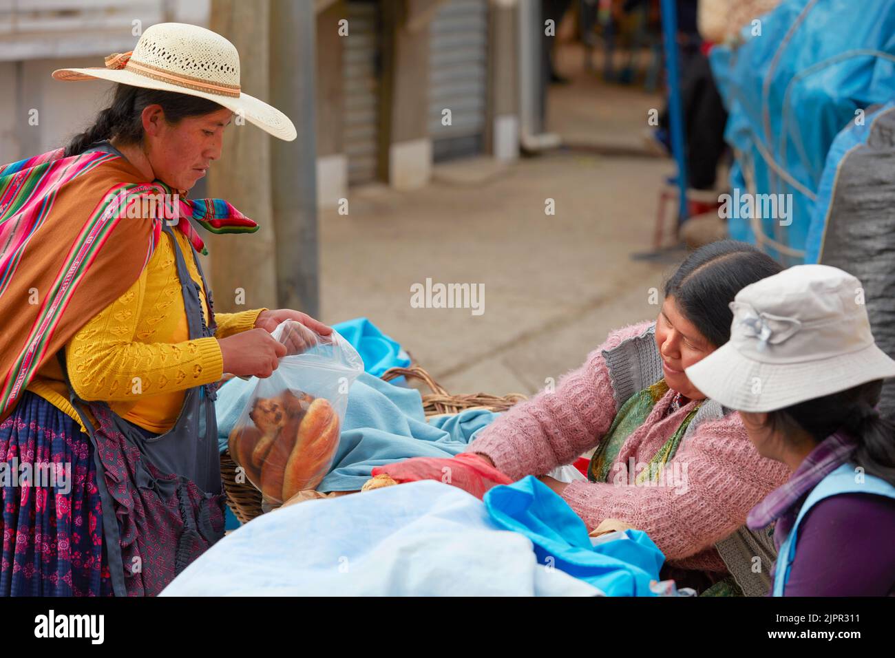 A Bolivian Chola woman buys bread in a stand at the Copacabana street market, Lake Titicaca, La Paz province, Bolivia. Stock Photo