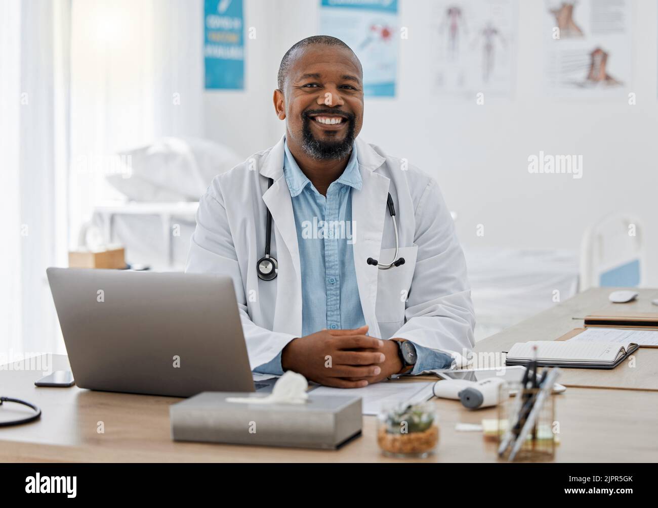 Doctor, medical healthcare worker and male physician at hospital or clinic working with stethoscope and electronics. GP man on laptop reading emails Stock Photo