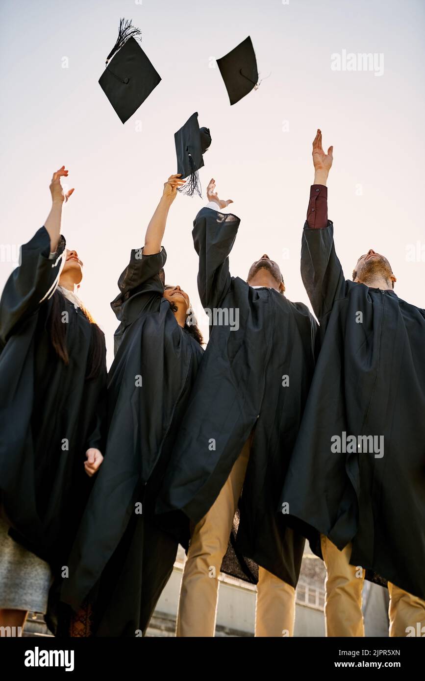 Its a big day of celebration. a group of students throwing their hats in the air on graduation day. Stock Photo