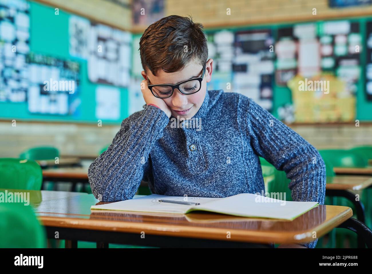 Catching a sneaky snooze. an elementary school boy sleeping at his desk in class. Stock Photo