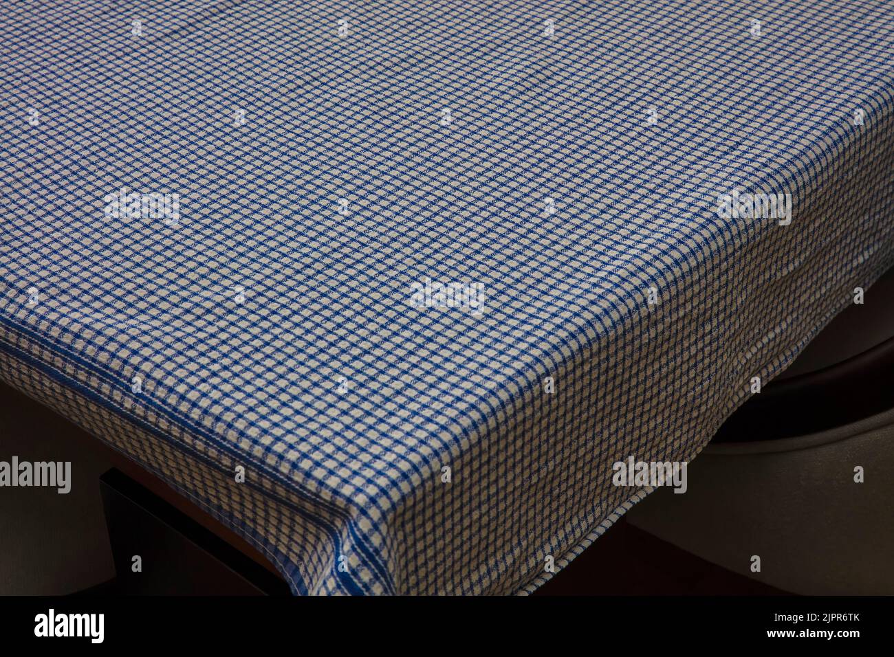 Blue and white chequered tablecloth on corner of empty table Stock Photo