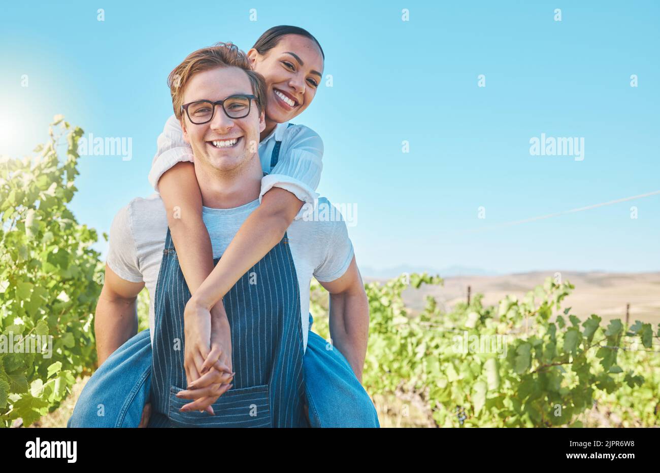 Happy and playful interracial farming couple with smile bonding with piggy back. Business people, man and woman agriculture worker in farming industry Stock Photo