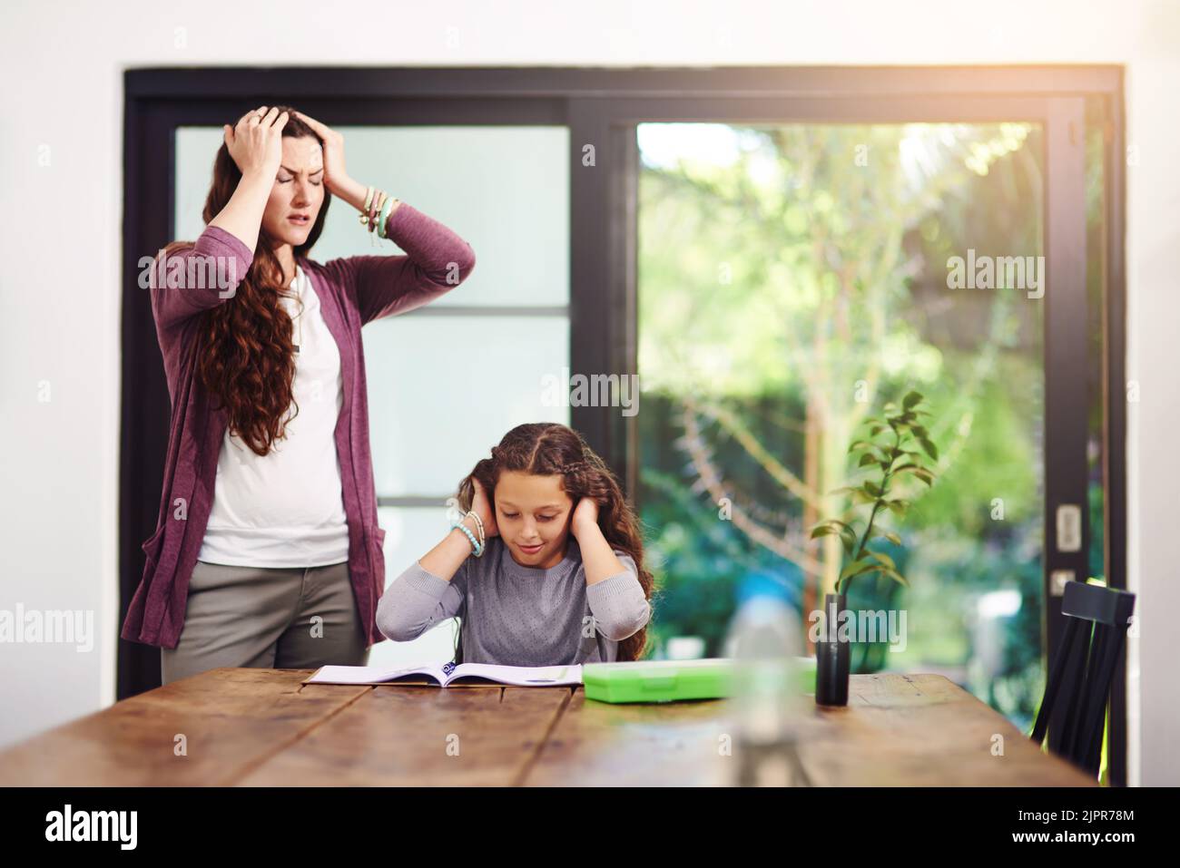 We just cant seem to figure out the answer. a young girl doing homework with her mother inside. Stock Photo