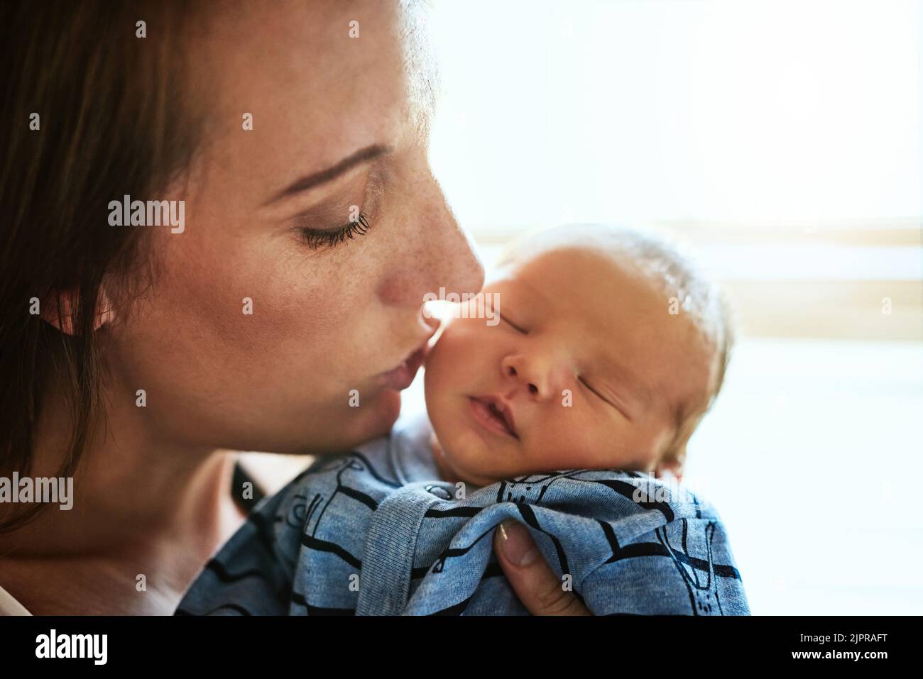 A mothers love. Closeup of a affectionate young mother giving her little baby boy a kiss on the
