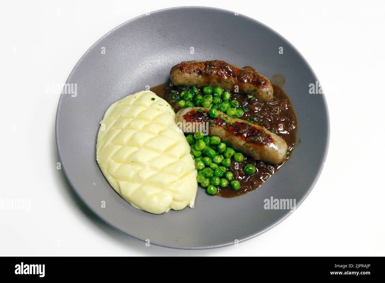 bangers and mash, grilled pork sausage with mash potato, brown onion gravy and steamed green peas Stock Photo