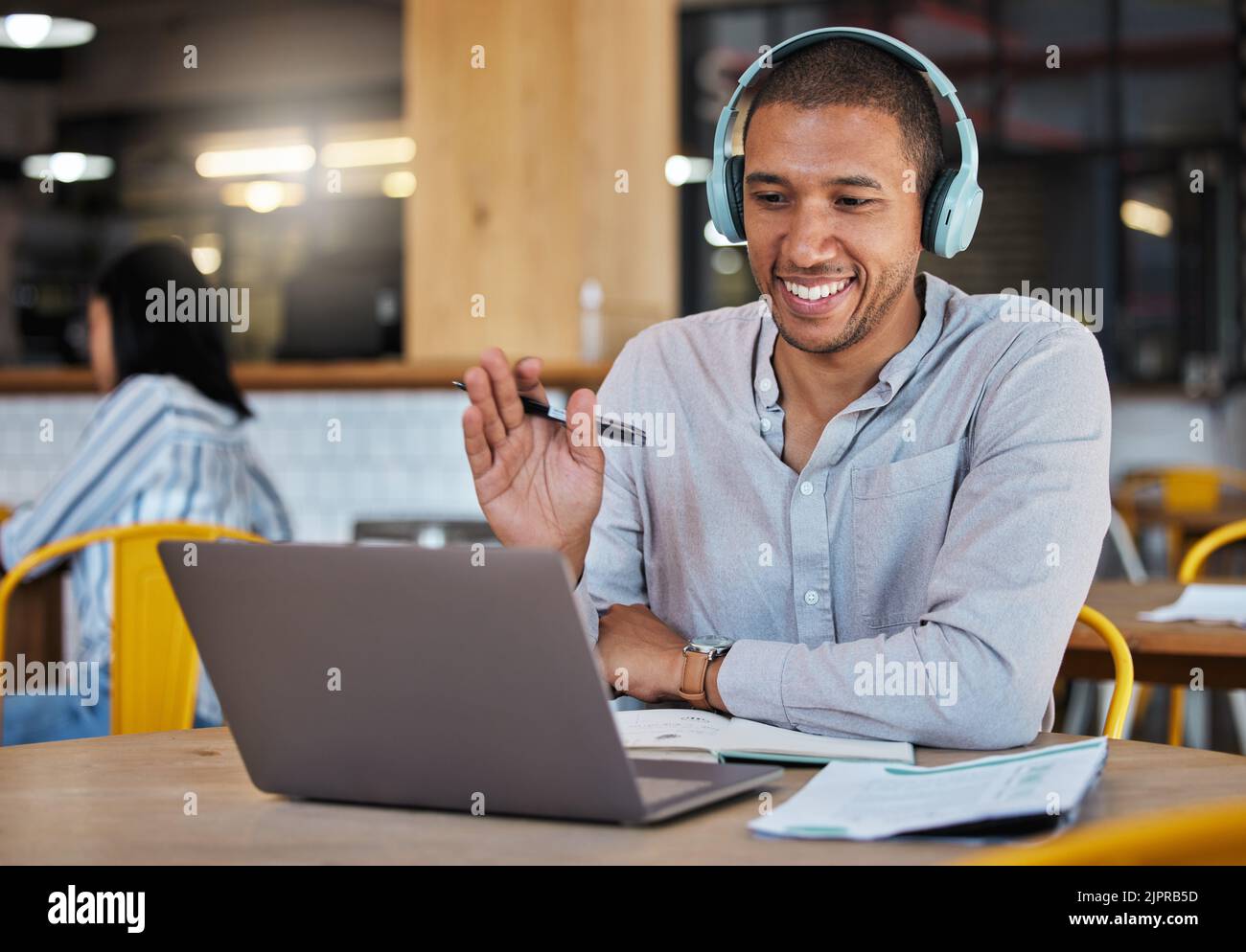 Man waving hands to greet hello on video call, online chat and virtual meeting with laptop webcam in a cafe. Happy freelance journalist and remote Stock Photo