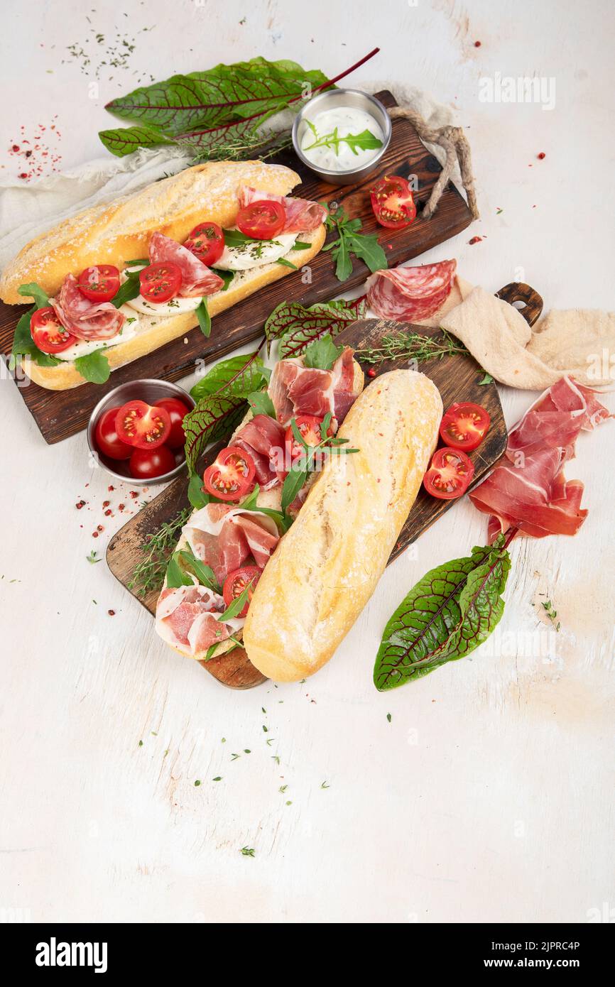 Two baguette sandwiches with salami, mozzarella cheese, lettuce