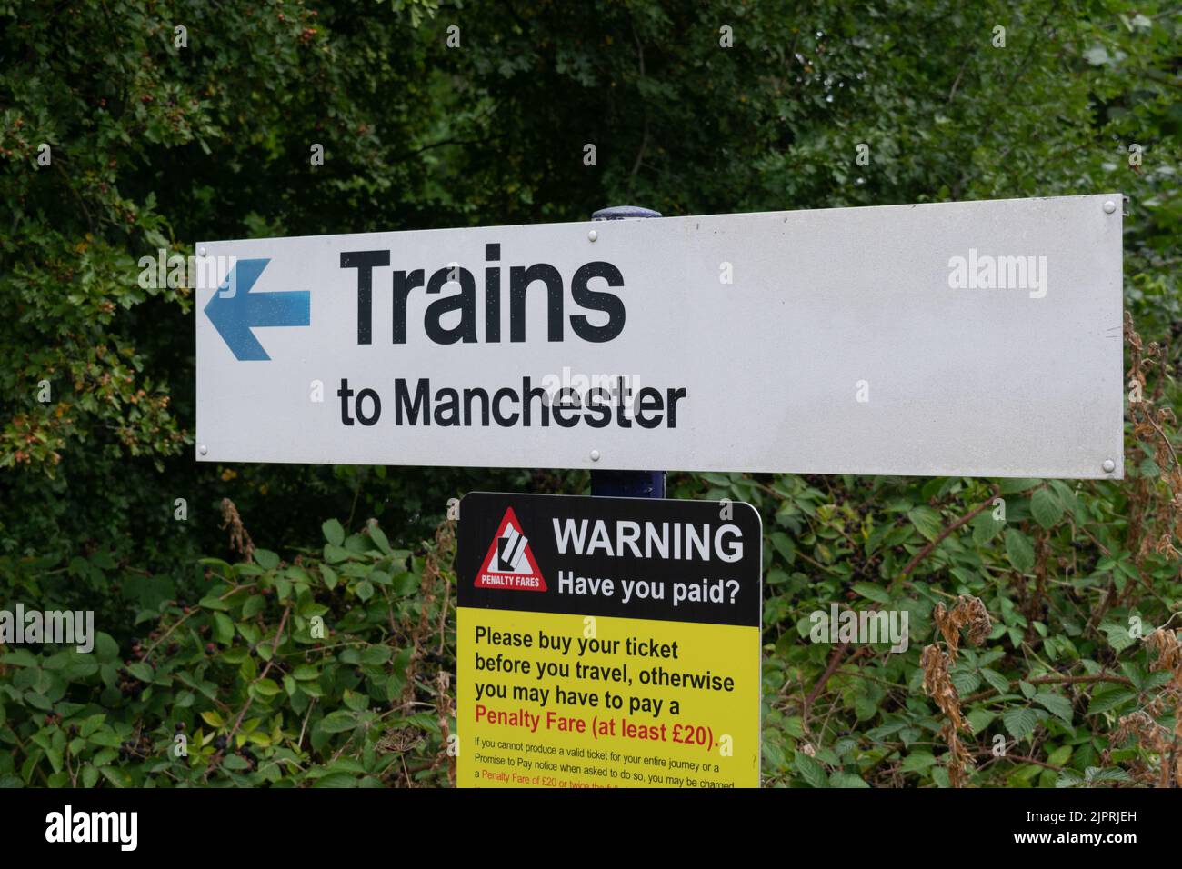 Sign at railway station text Trains to Manchester and warning sign text Have You Paid Stock Photo