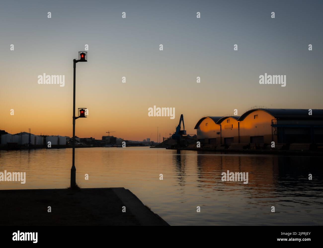 Sunrise over a harbour with navigation lights Stock Photo