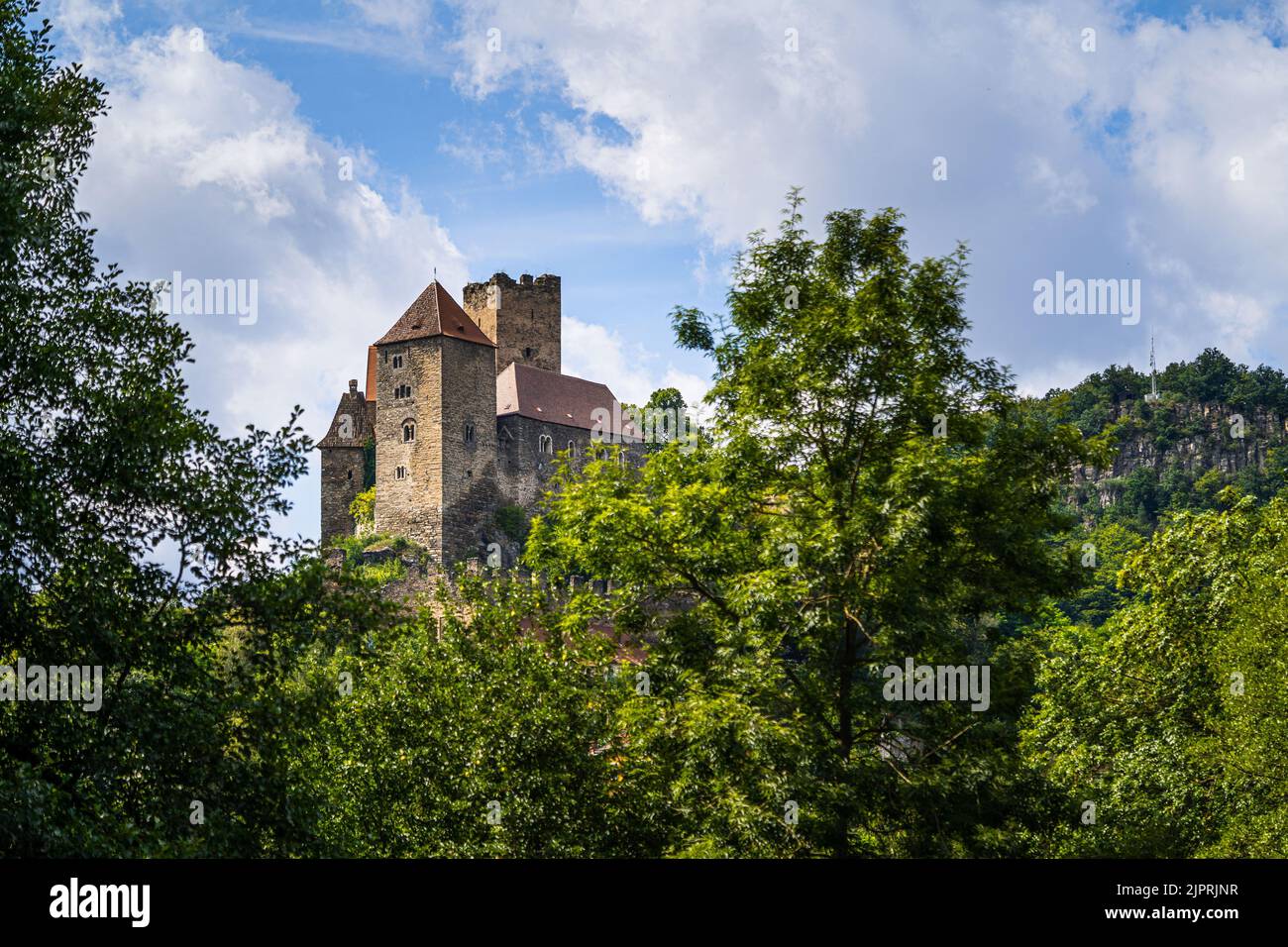 Medieval Burg Hardegg Castle in Austria through trees in slightly cloudy weather from a bit farther away. Stock Photo