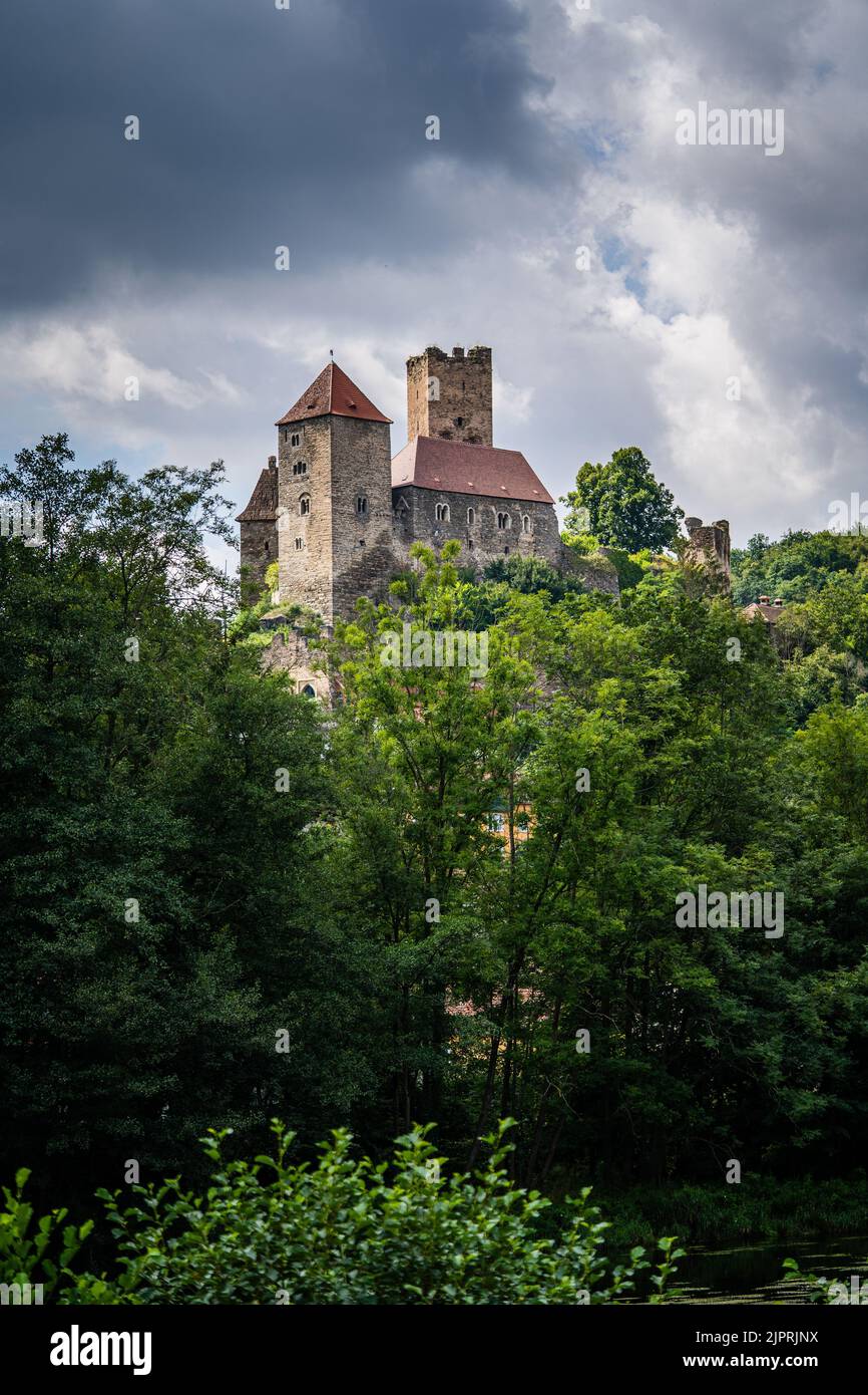 Medieval Burg Hardegg Castle in Austria through trees with dark clouds from a bit farther away. Stock Photo