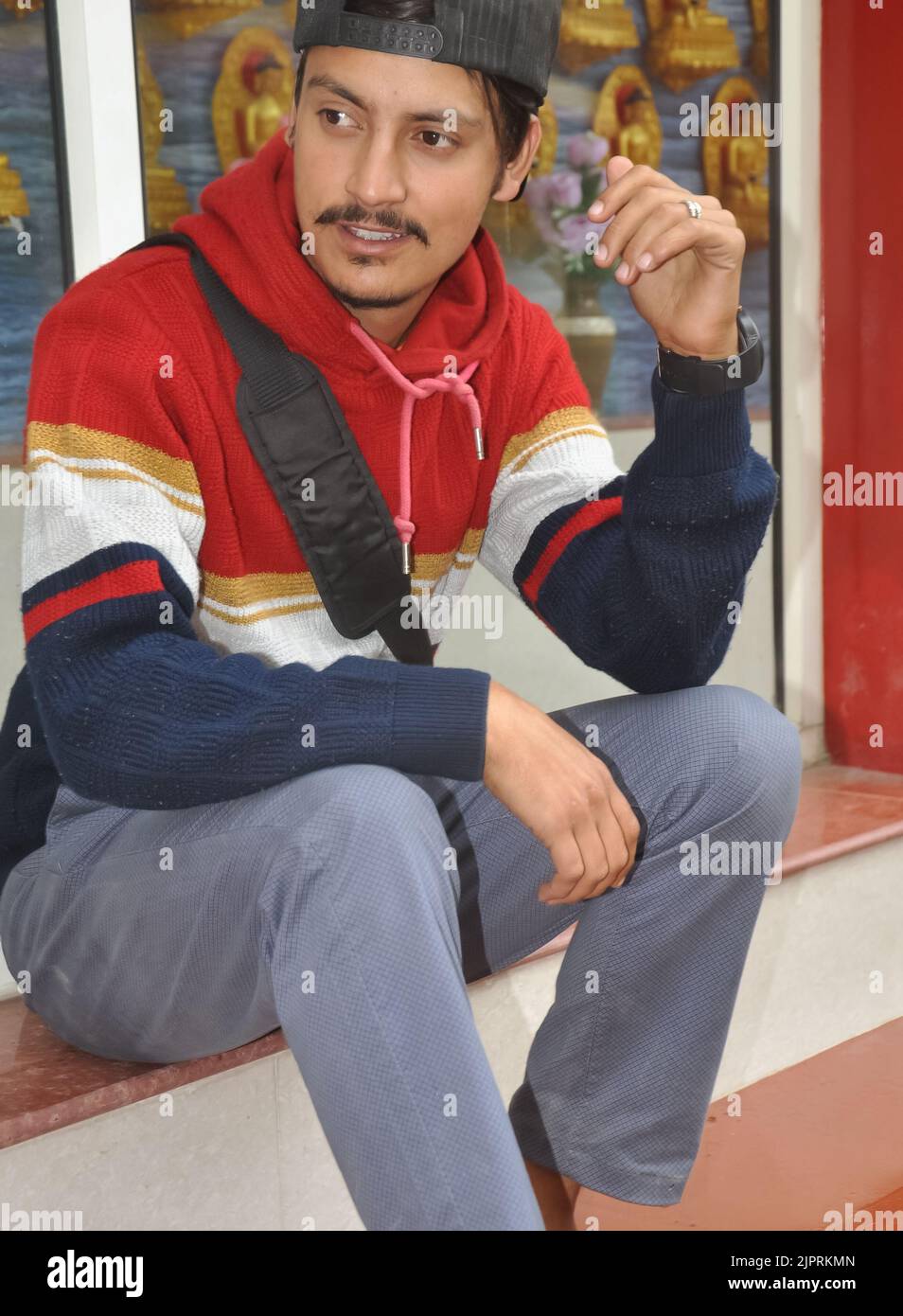 A young guy wearing cap backwards with looking sideways while sitting