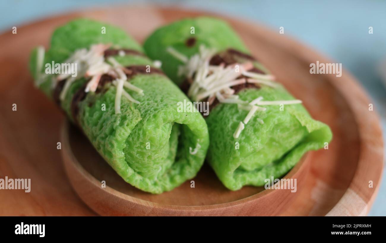 Pandanflavored green pancake rolls filled with pieces of coconut Stock