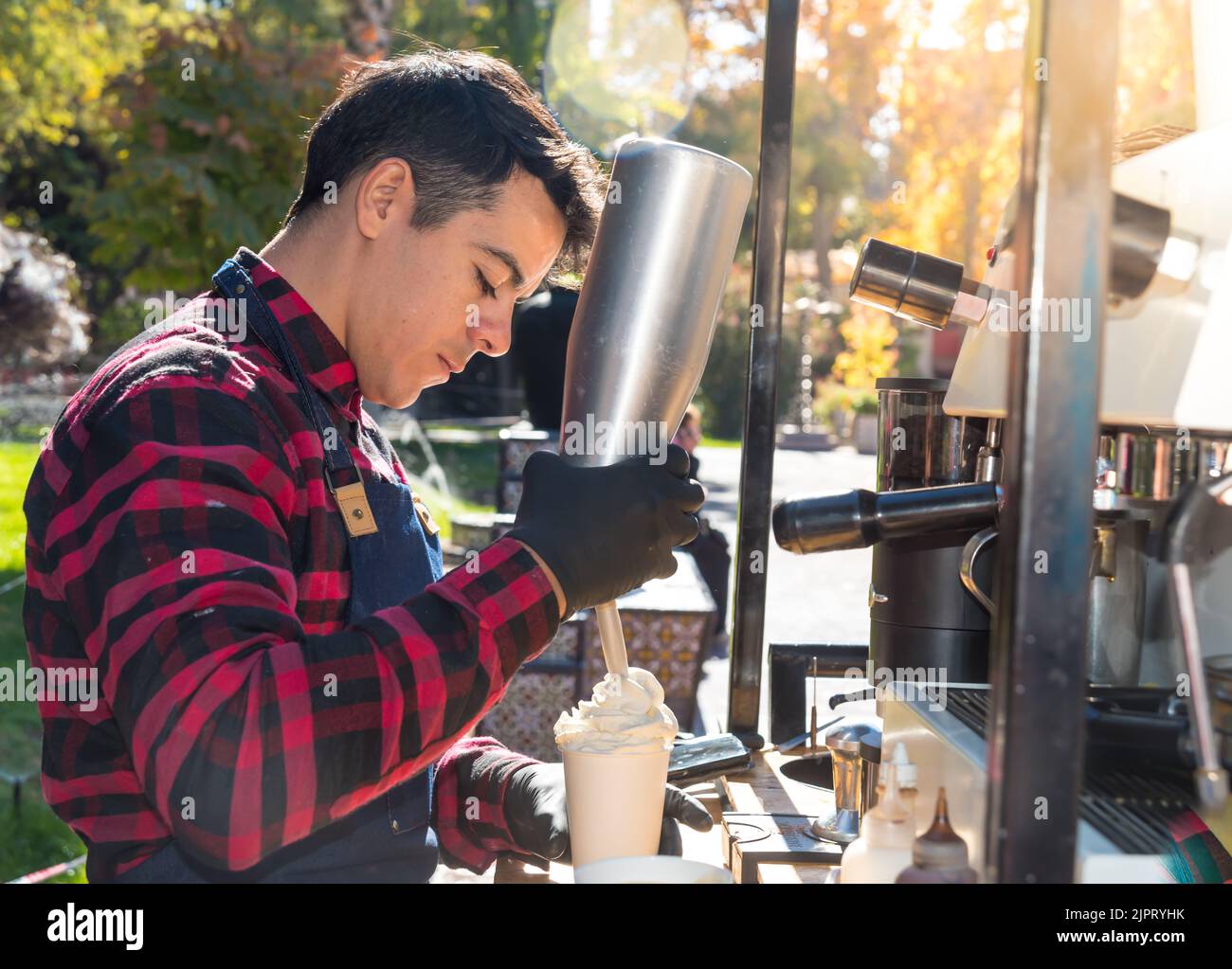 A young barista adding cream to coffee Stock Photo Alamy