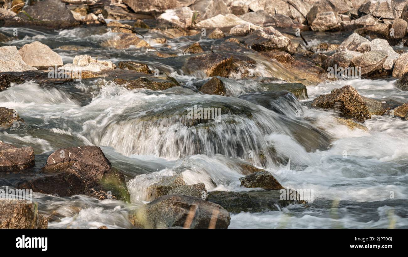 River flowing over rocks cascade on sunny day, closeup detail - longer exposure photo Stock Photo