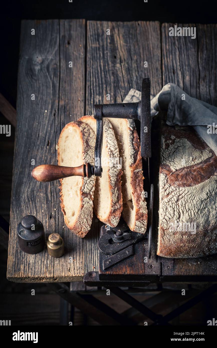 https://c8.alamy.com/comp/2JPT14K/crunchy-and-fresh-loaf-of-bread-with-on-old-slicer-a-loaf-of-bread-on-a-crumb-slicer-2JPT14K.jpg
