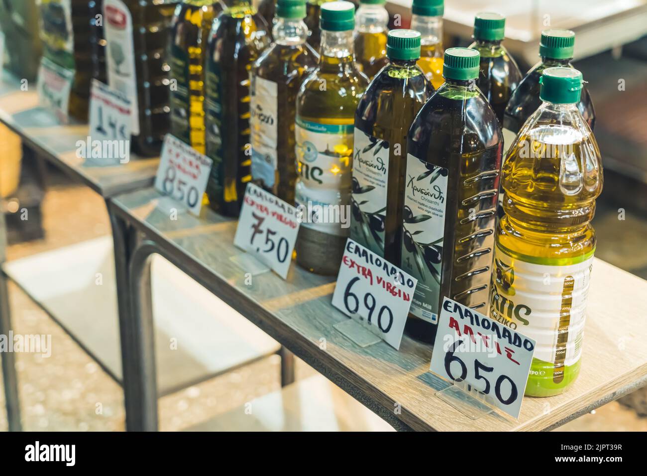 07.13.2022 Thessaloniki, Greece. Different kinds of pure Greek olive oil in plastic and glass transparent bottles with green caps standing on a display at the famous Kapani Market. High quality photo Stock Photo