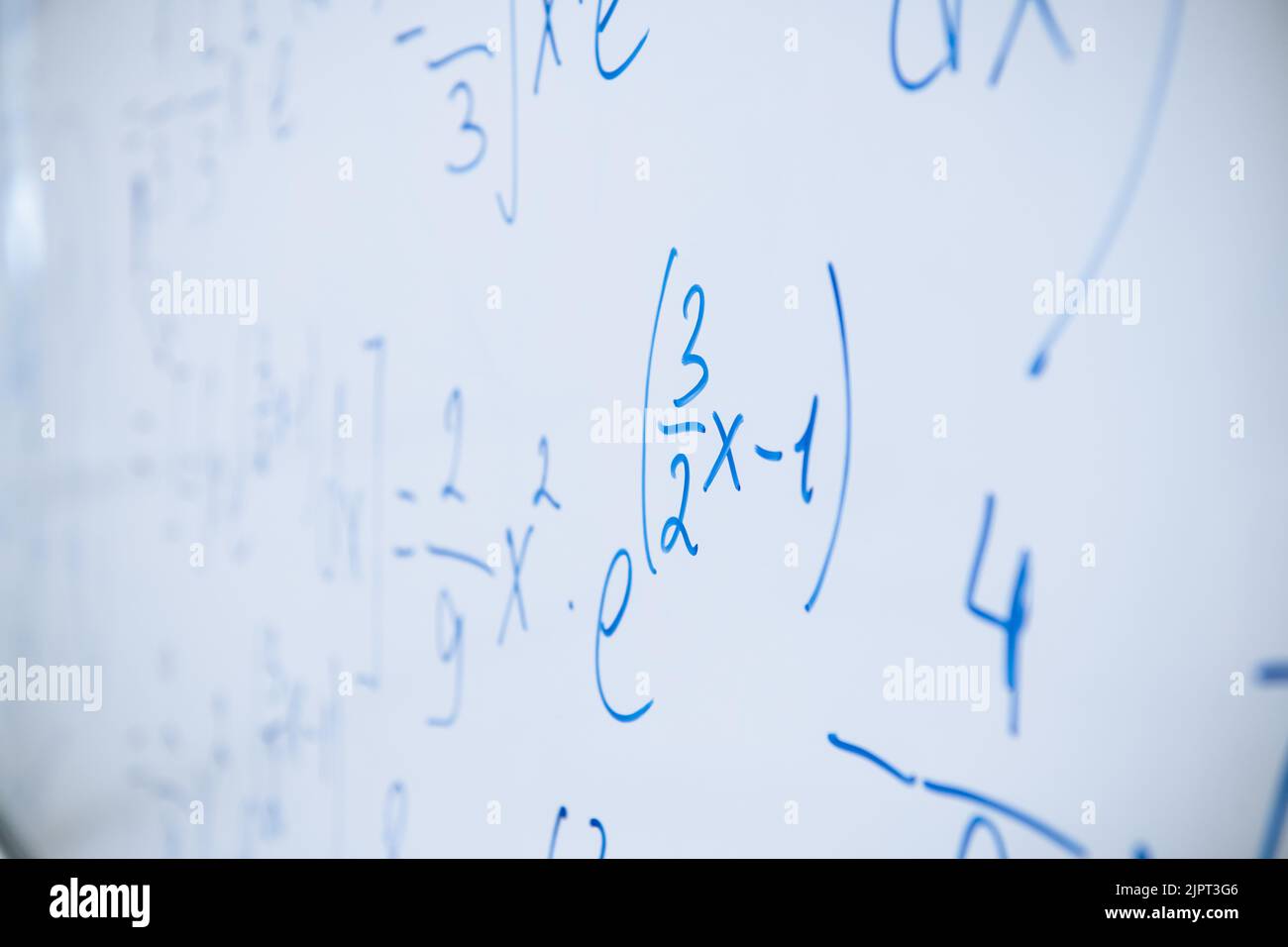 Physical and mathematical formulas written with a blue marker on a white board in a high school classroom. Abstract background close-up. Stock Photo