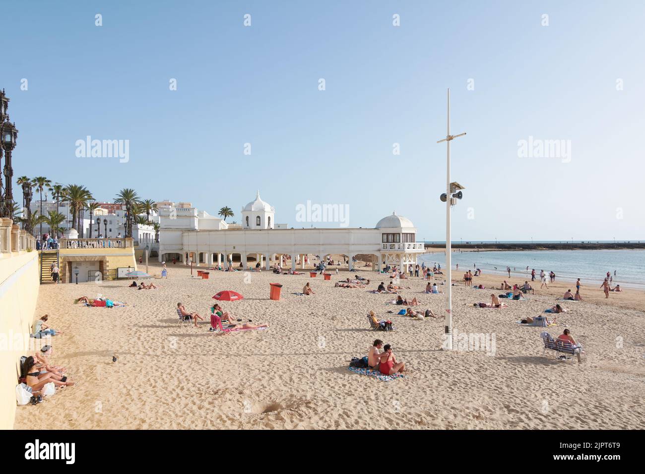 CADIZ, ESPAÑA -15 DE ABRIL DE 2022: Playa de la Caleta en Cádiz con gente, una farola en primer plano y la oceanografía en segundo plano. Stock Photo