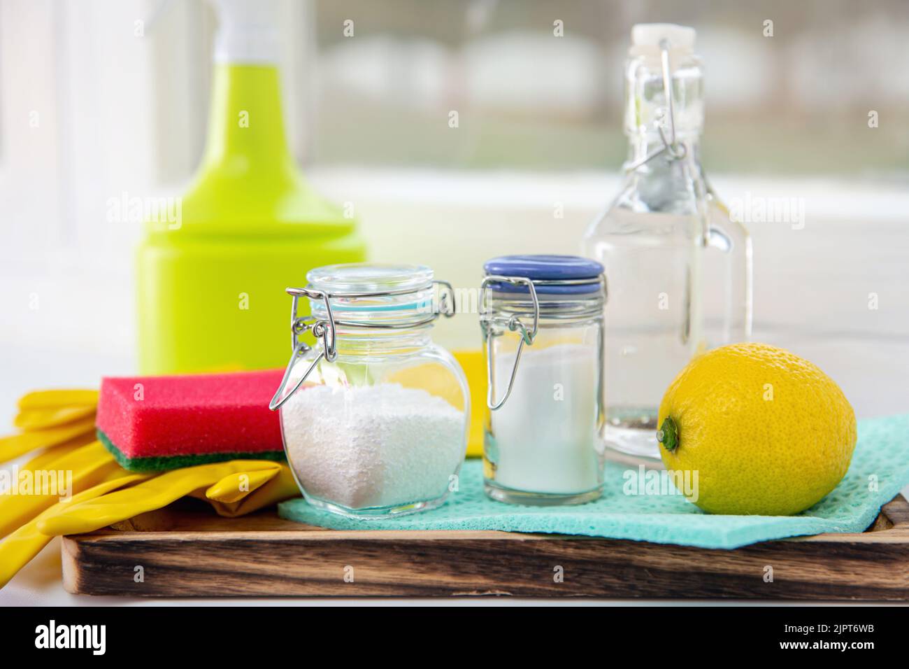 Natural organic eco friendly home cleaning tools ingredients, white vinegar, lemon, baking soda, citric acid on wood tray on window sill, window. Stock Photo