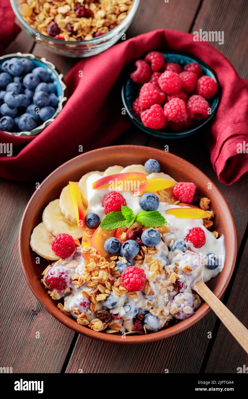 Greek yogurt with granola, berries and fruits on a wooden table