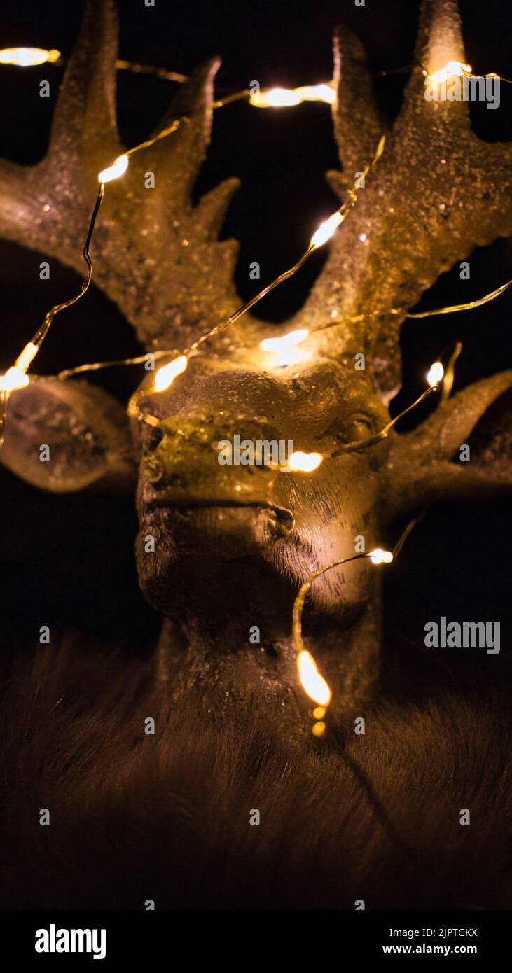 The vertical view of a deer statue decorated with Christmas lights